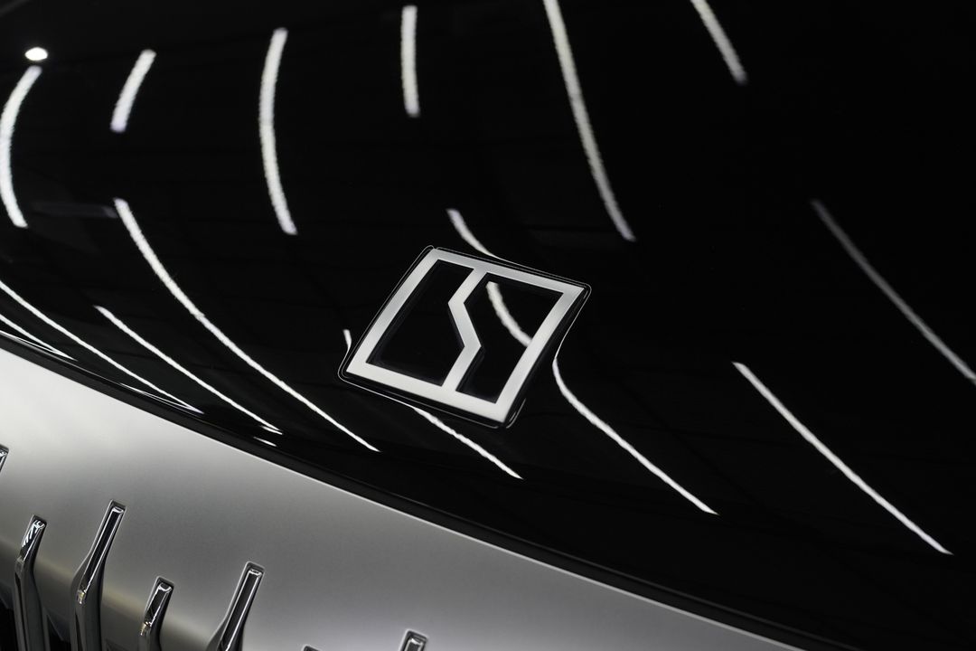 Close-up of the ZEEKR emblem on the glossy black bonnet with light reflections across the paint.