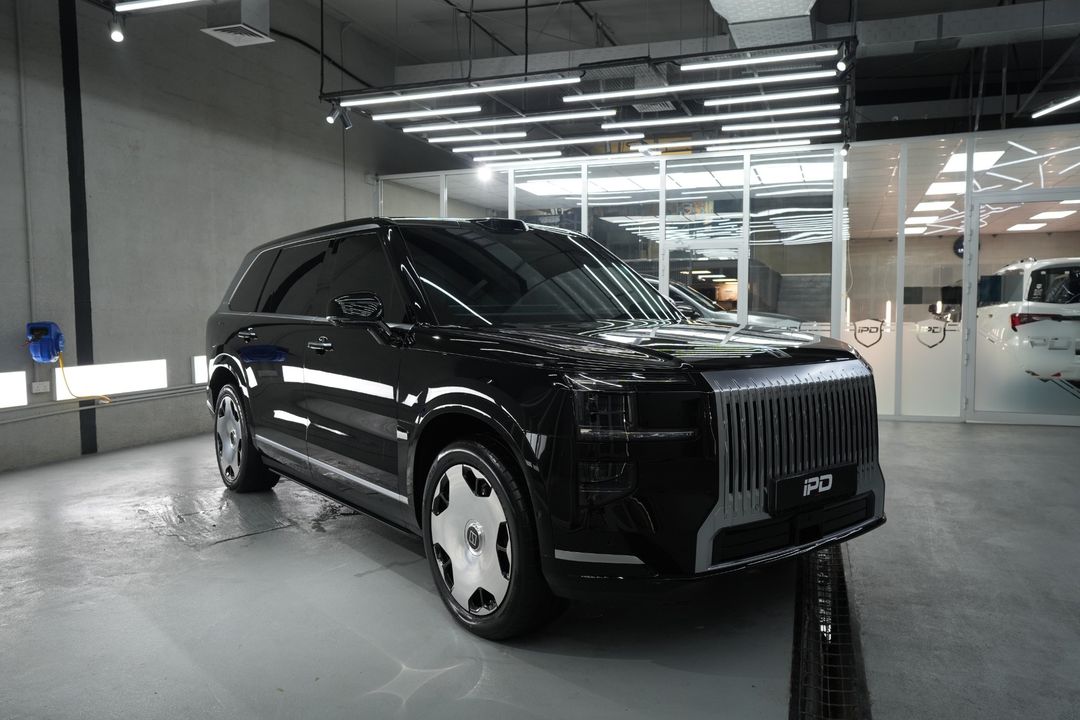Black ZEEKR 9X in the IPD studio, seen from the front three-quarter, with a tall silver grille and silver wheels.