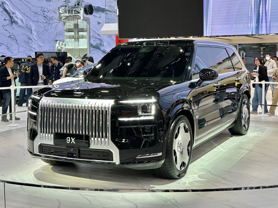 A black ZEEKR 9X on a show stand at Auto Shanghai 2025, seen from the front three-quarter, with visitors behind it.